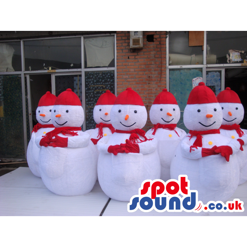 Seven Snowmen Mascots Wearing A Red Scarf, Gloves And Hat -